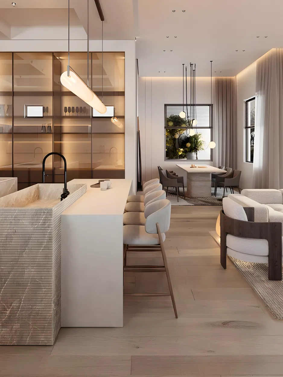 A modern open-concept living space with a minimalist kitchen island, bar stools, cozy seating area, and a dining table. Warm lighting and contemporary decor by interioritalia deliver a residential interior fit out that feels both inviting and stylish.